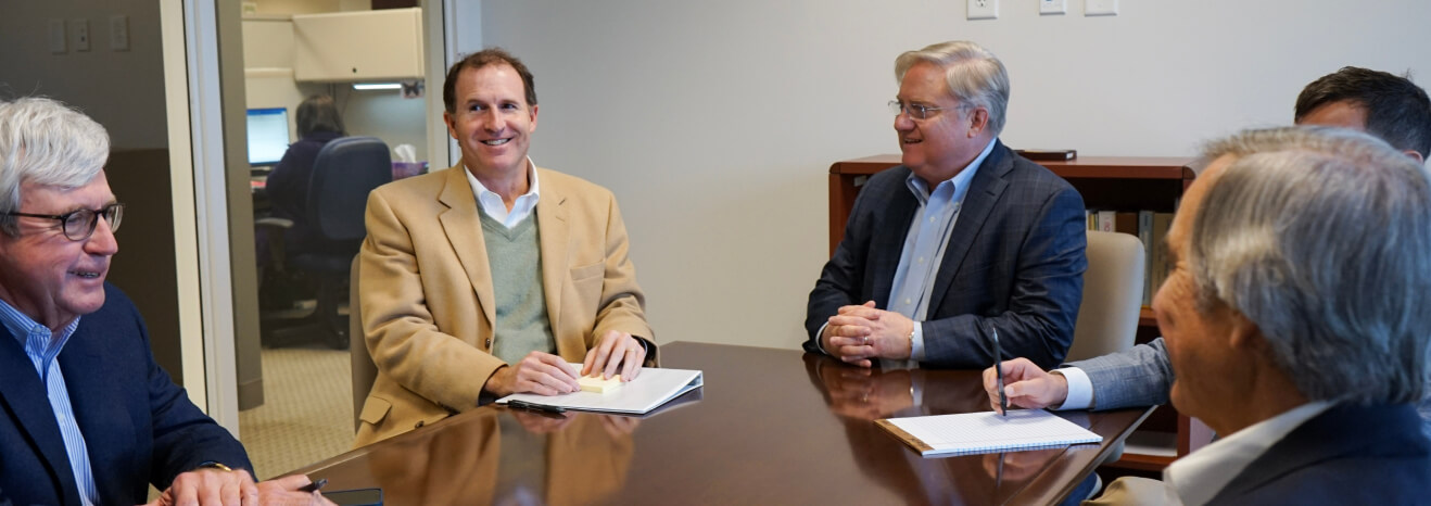 4 Yates employees sitting at a conference table discussing their insurance careers.