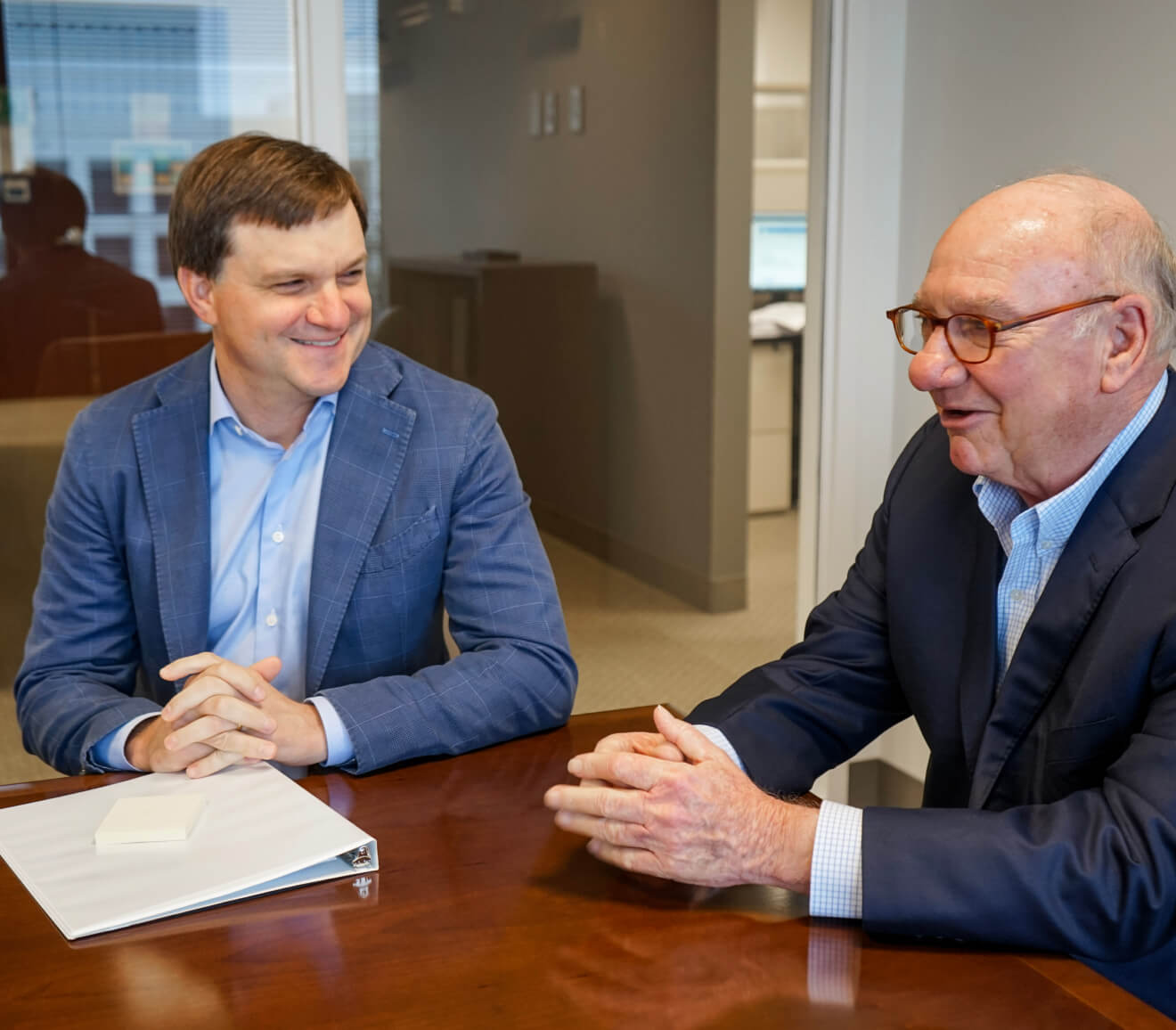 2 male Yates employees sitting at a conference table talking discussing insurance careers.